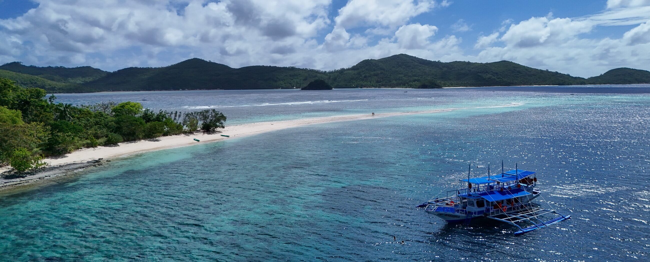 Aerial view of a coastline with a boat anchored near the shore