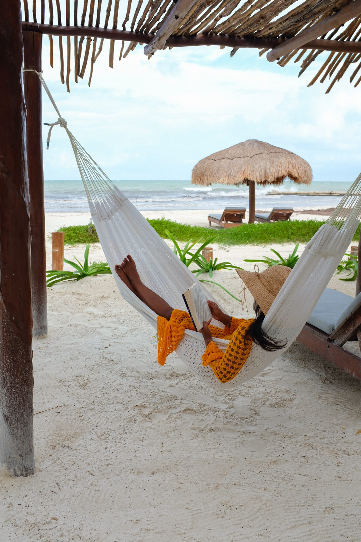 A person reading in a hammock by the beach
