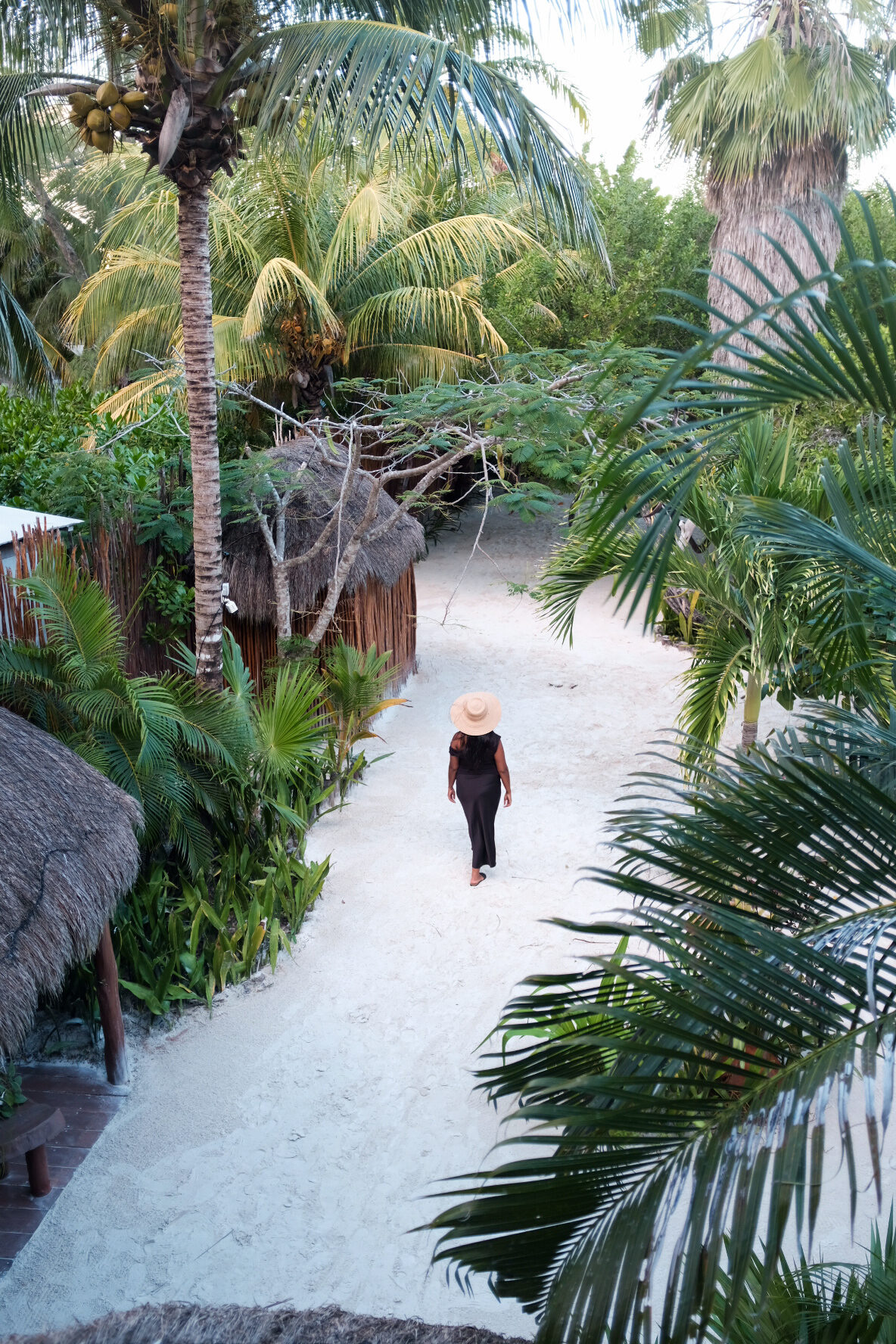 Walking toward a beach hut in a sunhat