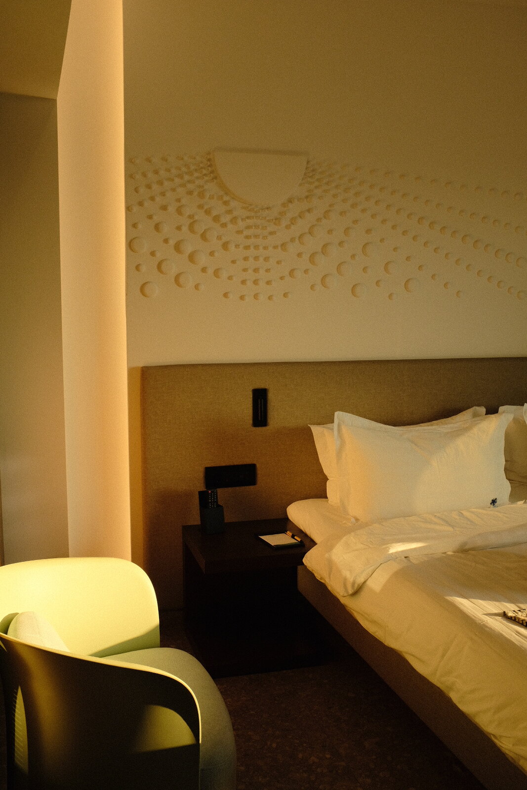 Hotel bed with sculpted wall art above the headboard