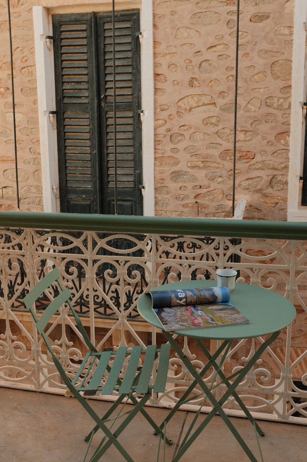 Bistro table on a stone balcony with shuttered windows